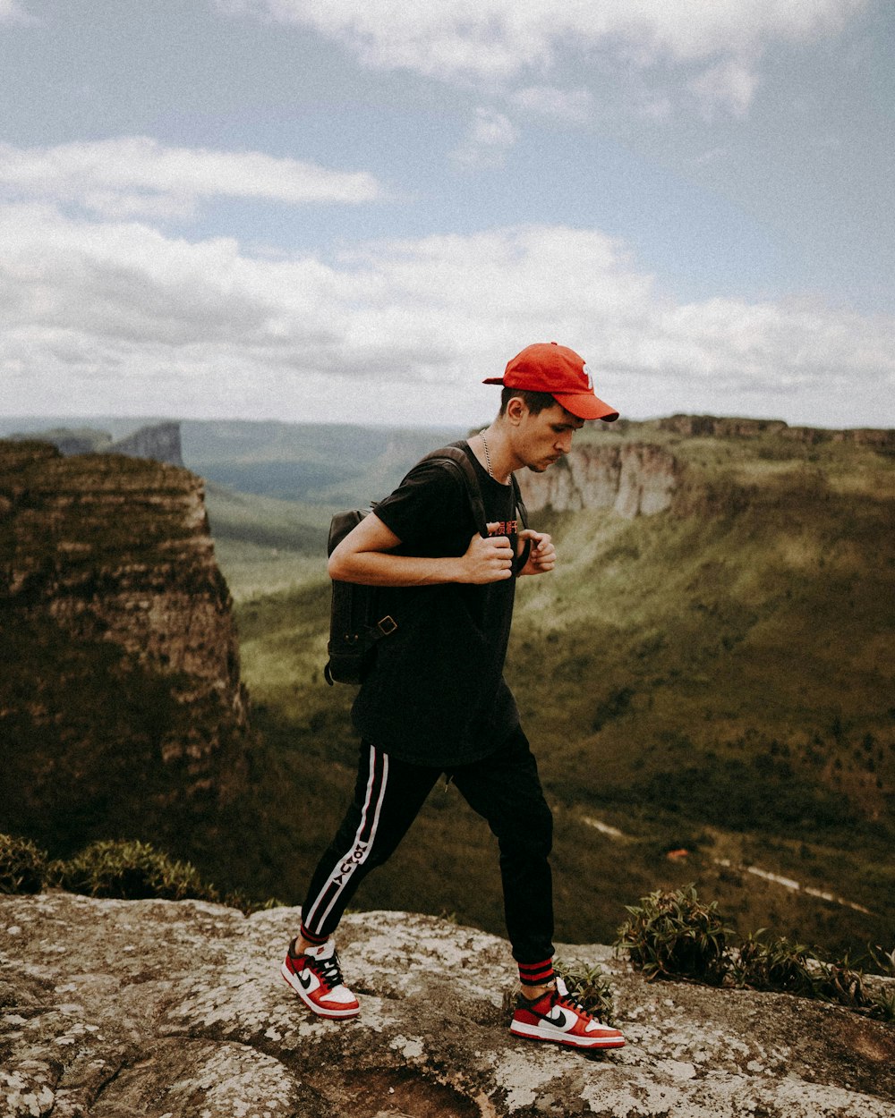 man in black t-shirt and black pants standing on rock during daytime