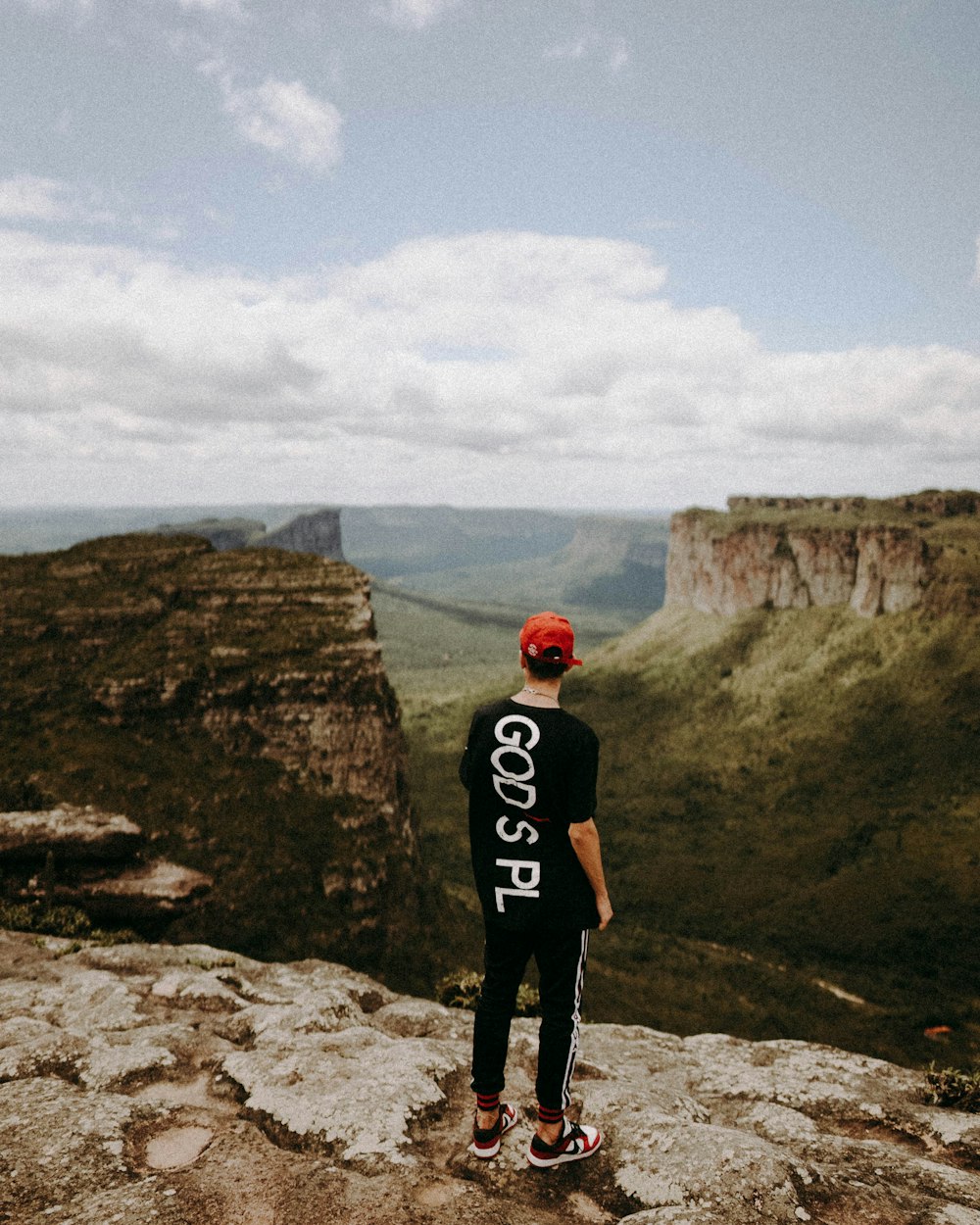 man in black t-shirt standing on rocky hill during daytime