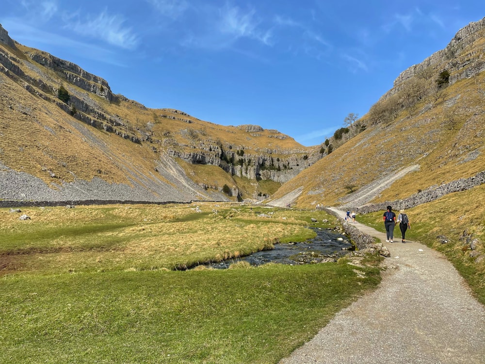 people walking on pathway near mountain during daytime