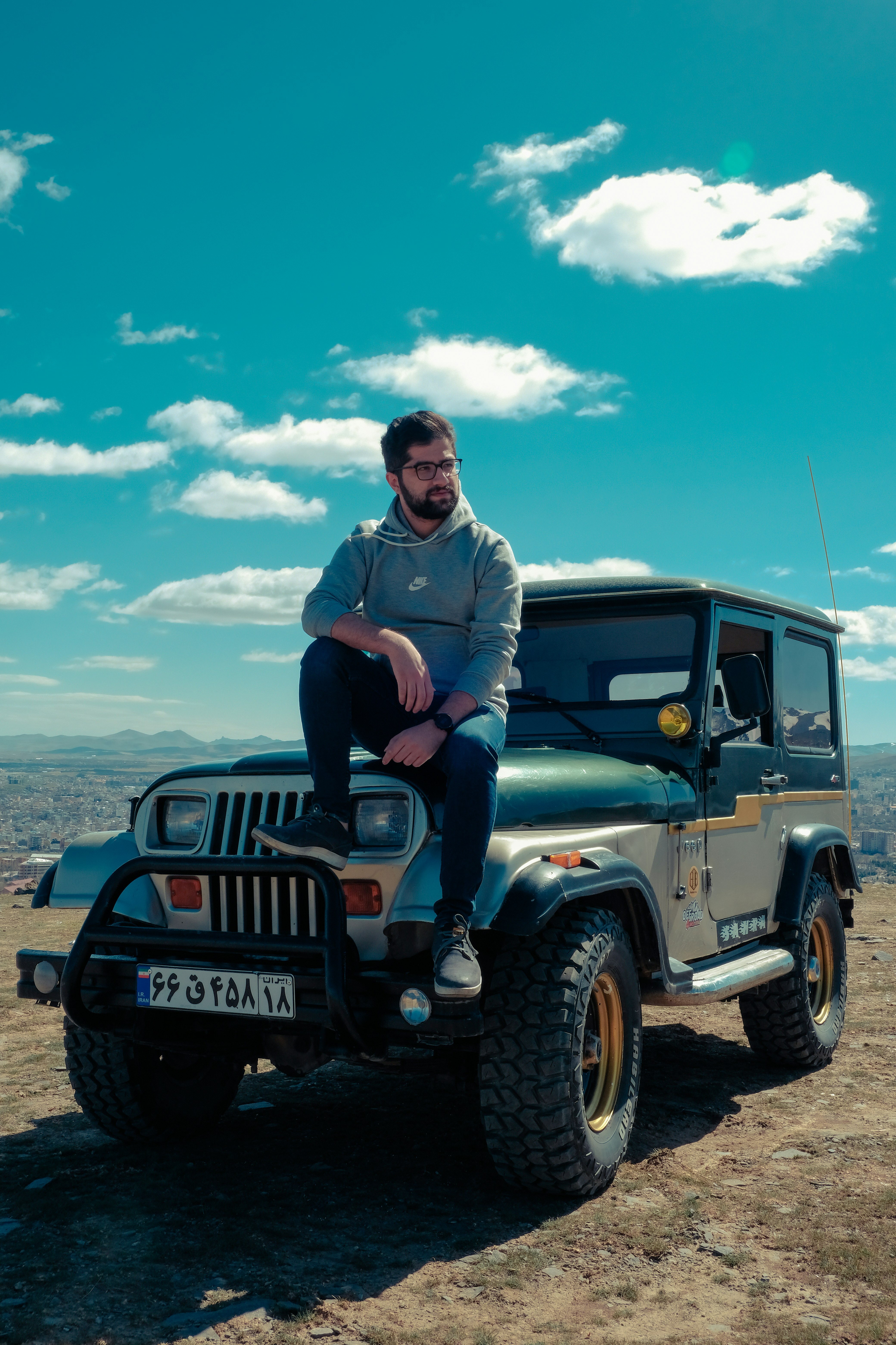 man in gray jacket sitting on black jeep wrangler