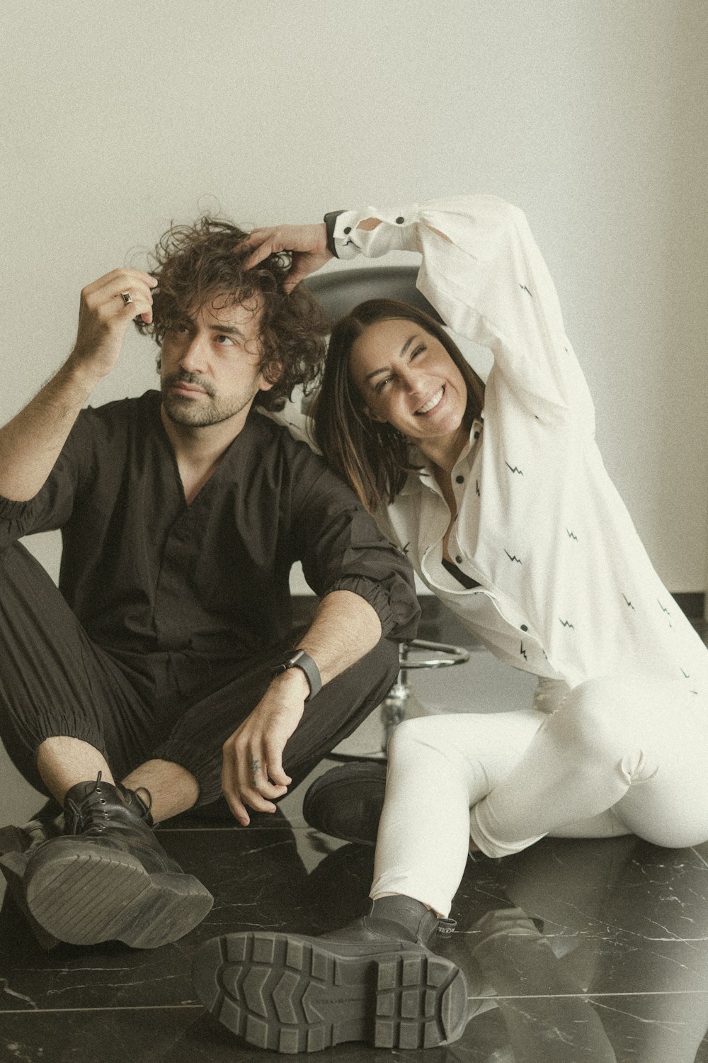 man and woman sitting on white bed