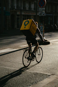 Courier on a bike delivering a package in a sunny urban neighborhood.