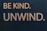 Bold yellow text on a dark background reads 'BE KIND. UNWIND.' The words are evenly spaced and capitalized, conveying a message of encouragement and relaxation.