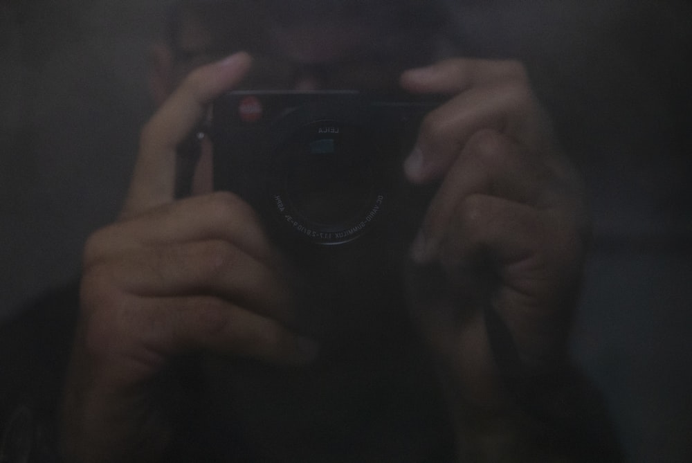 person holding black camera taking selfie