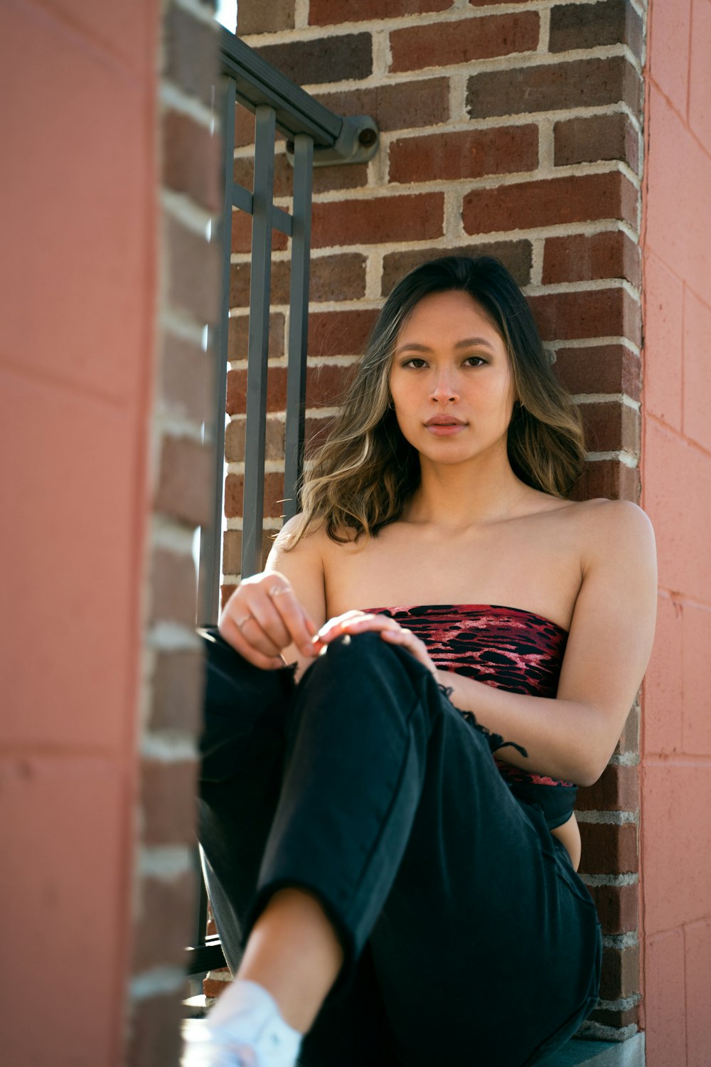 woman in blue tube dress leaning on brown brick wall