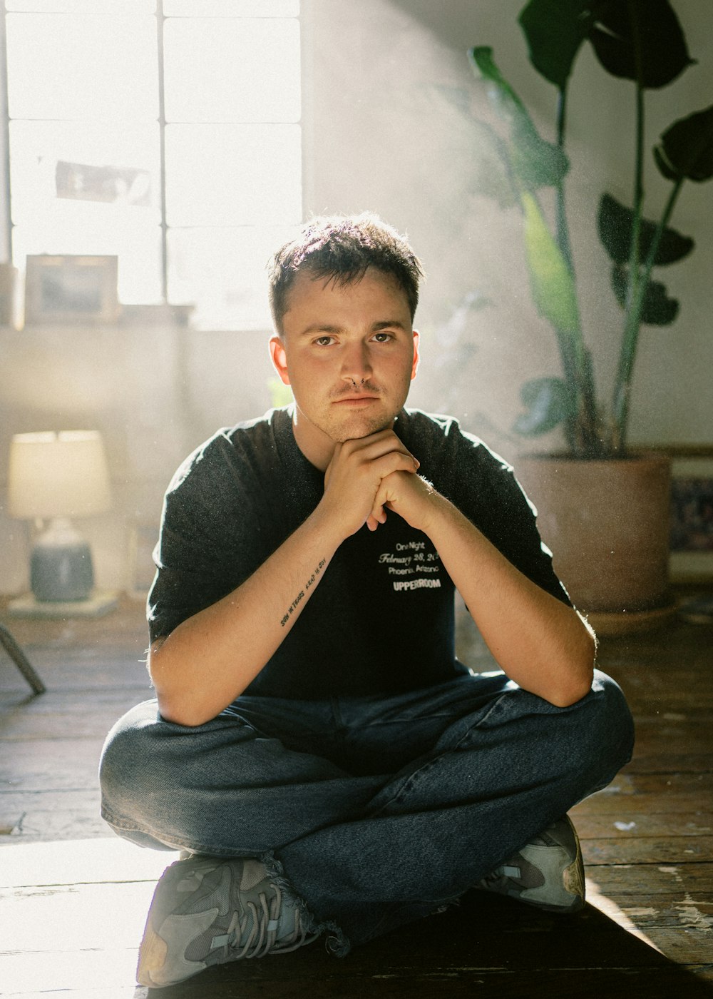 man in black crew neck t-shirt and blue denim jeans sitting on floor