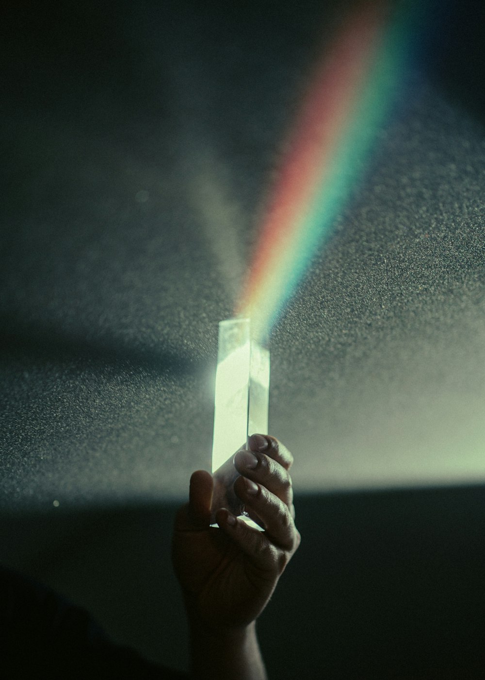 Persona sosteniendo caja blanca con luz de arco iris