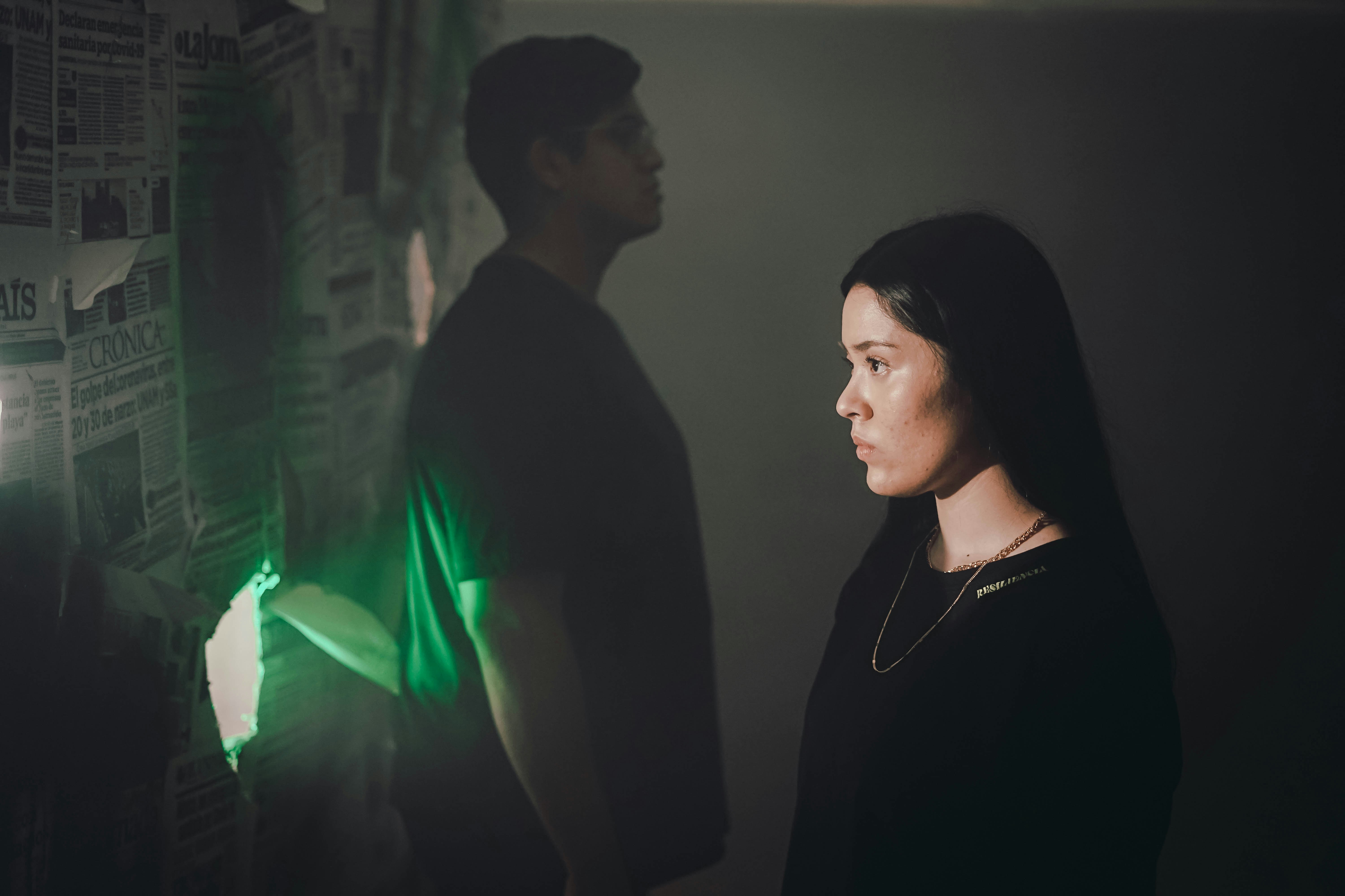 man in black shirt standing beside woman in green dress