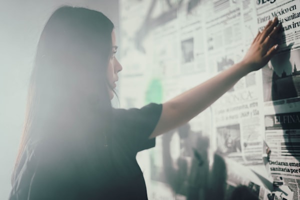 woman looking at a wall of newspapers