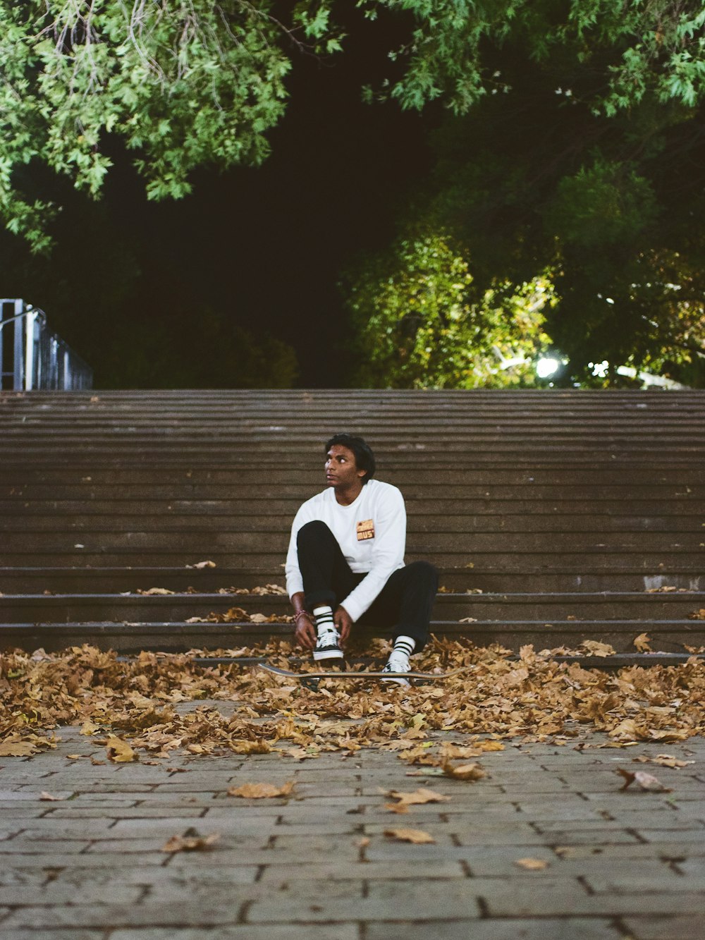 man in white shirt and black pants sitting on brown wooden bench