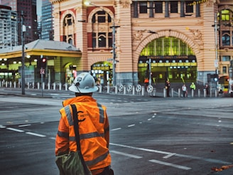 man in orange and black backpack walking on pedestrian lane during daytime