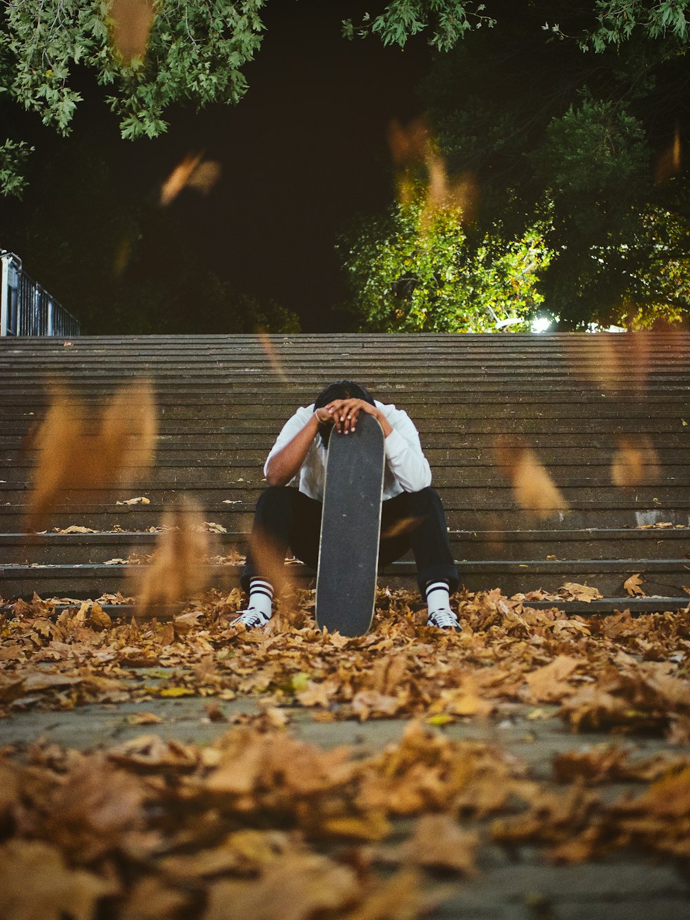 person in black jacket and black pants sitting on brown wooden bench during daytime