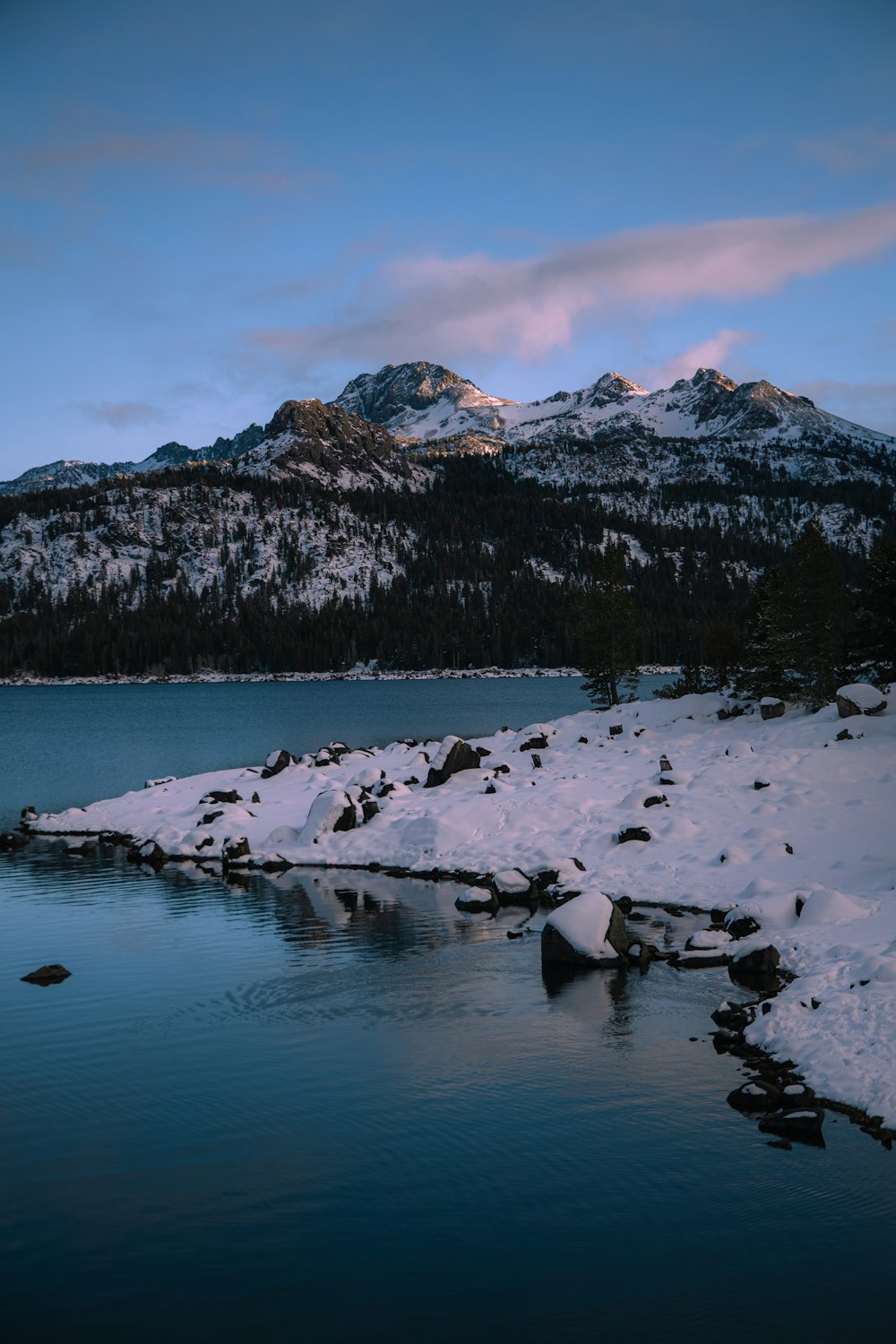 snow covered mountain near body of water during daytime