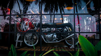 A vibrant motocross bike displayed in a showroom with San José del Guaviare landscape visible through the window.