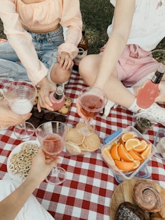 Hands holding glasses of wine over a picnic basket