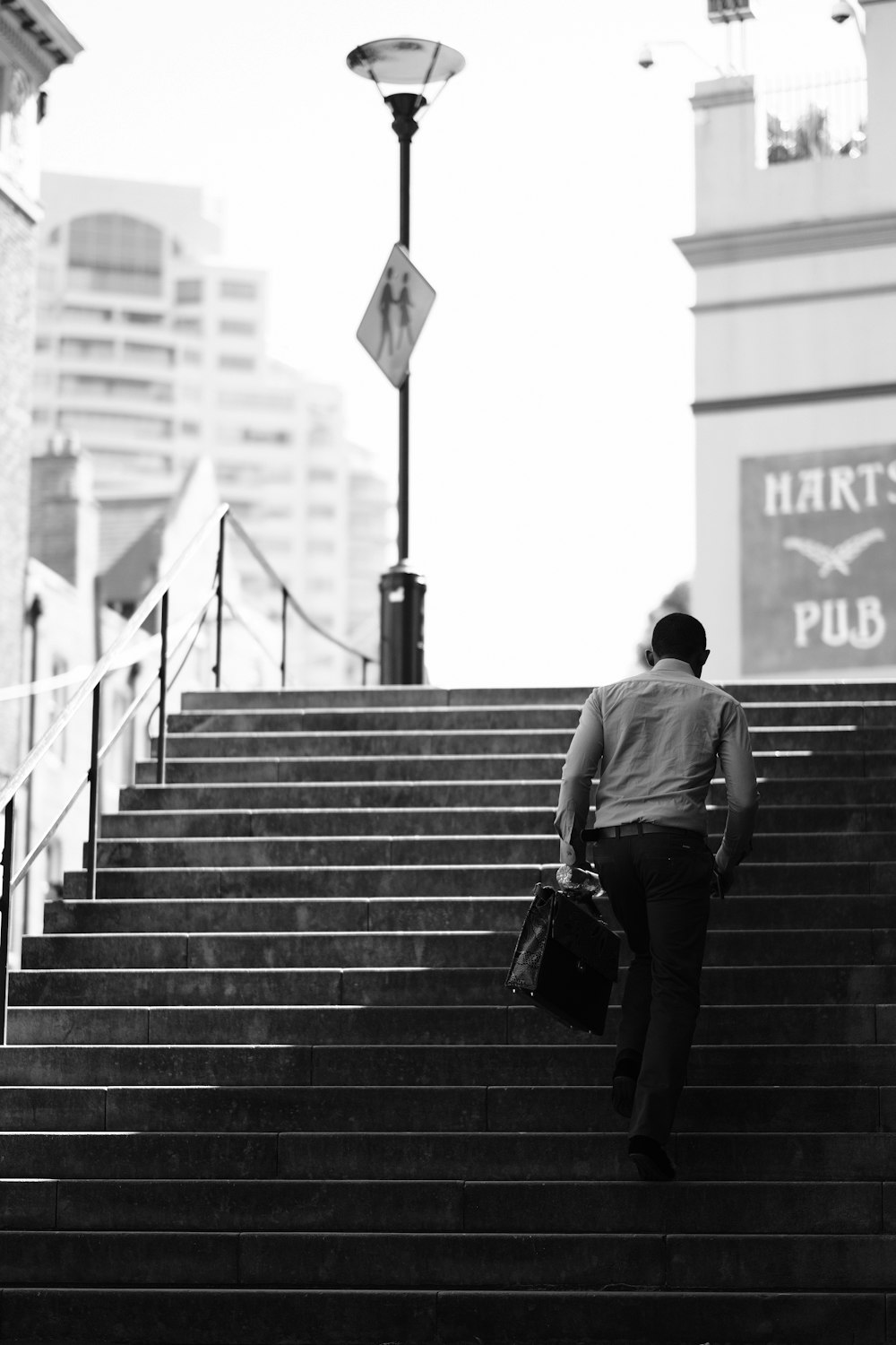 Hombre con camiseta negra y pantalones negros caminando por las escaleras