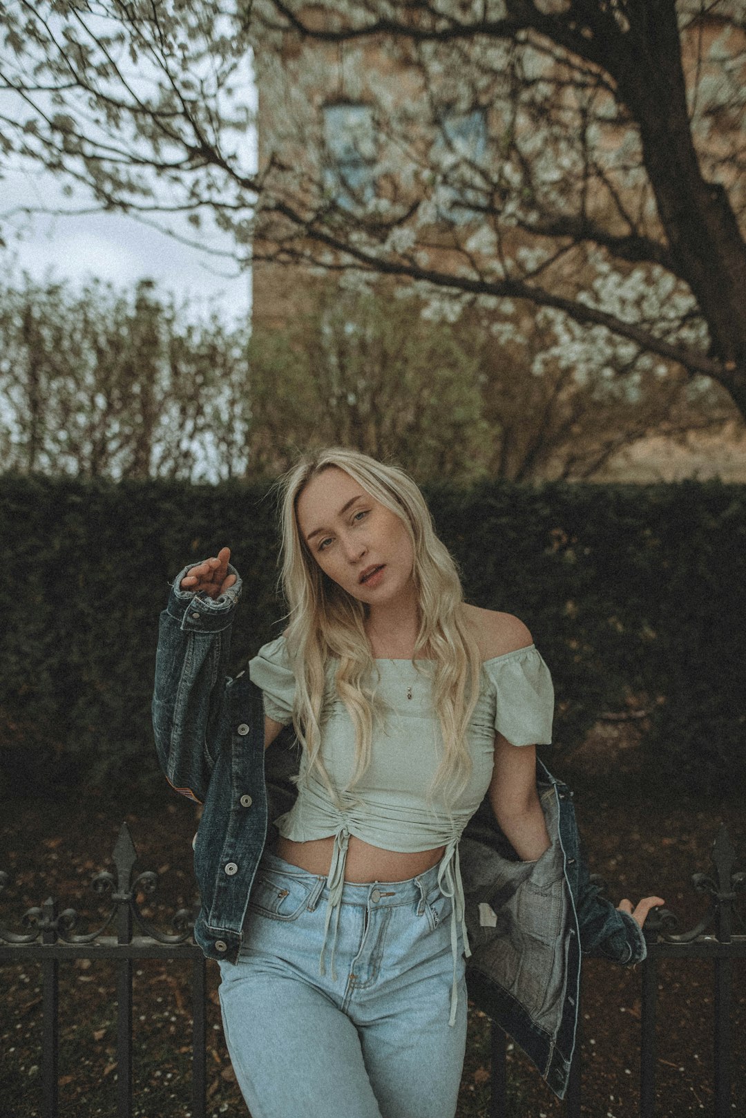 woman in gray denim jacket standing near bare trees during daytime