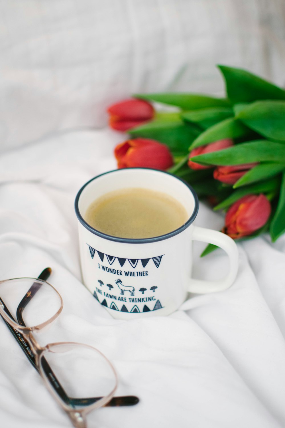 Taza de cerámica blanca con café sobre textil blanco