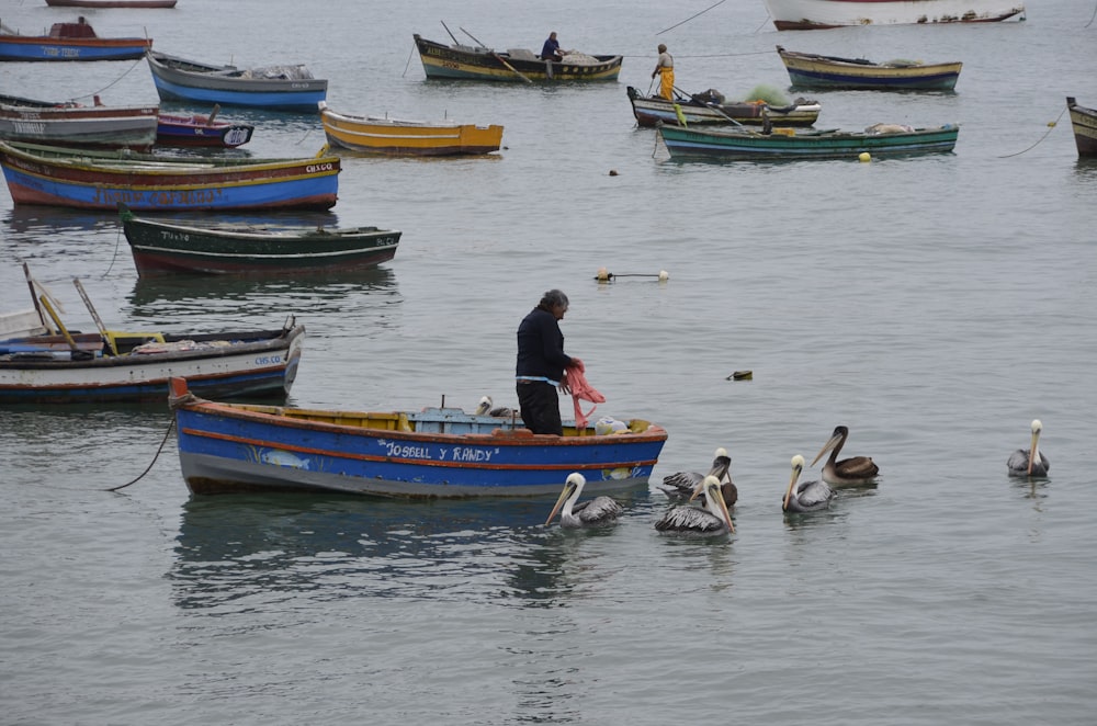 man in black jacket riding on red and blue boat on water during daytime