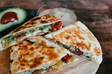 Grilled quesadilla slices served with salsa and guacamole on a wooden board.