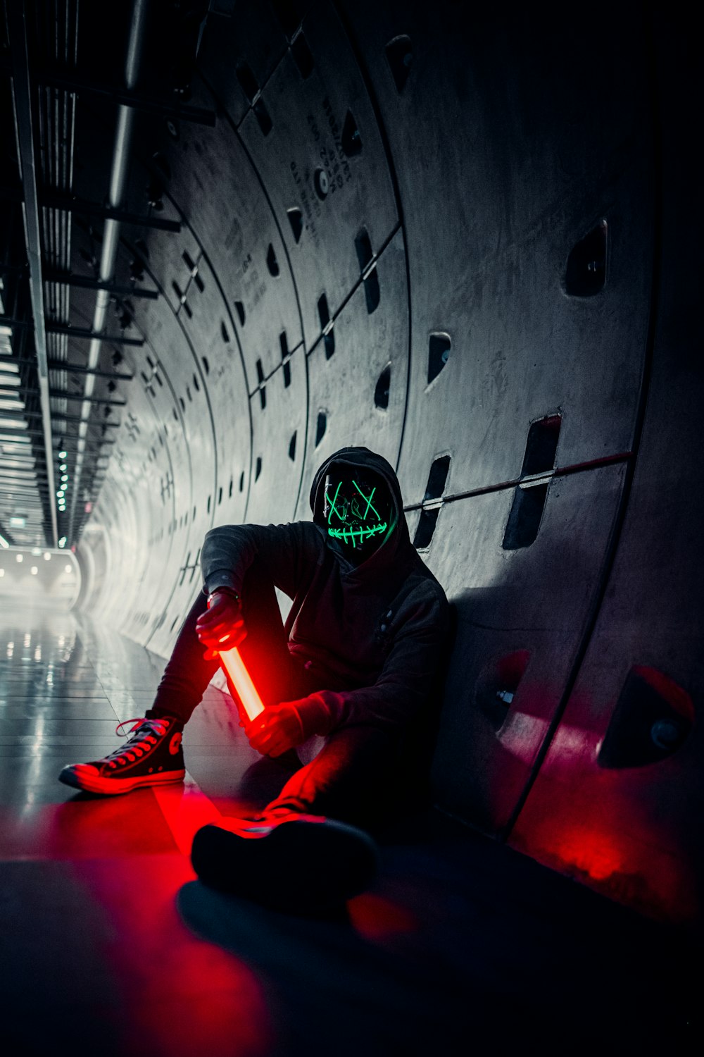 Homme en costume noir et rouge portant un casque assis sur un tunnel