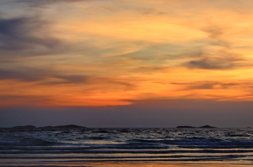 ocean waves crashing on shore during sunset