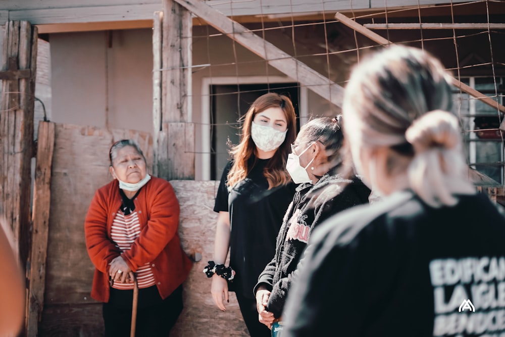 group of people standing near brown brick wall