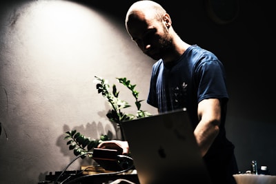 A person filming a video review in a softly lit room with plants in the background.