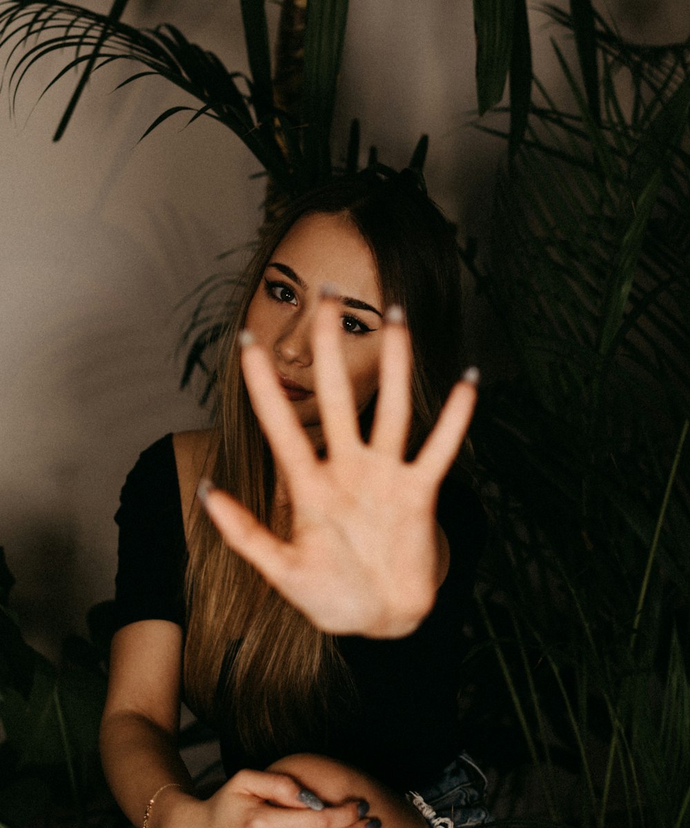 woman in black shirt covering her face with her hand