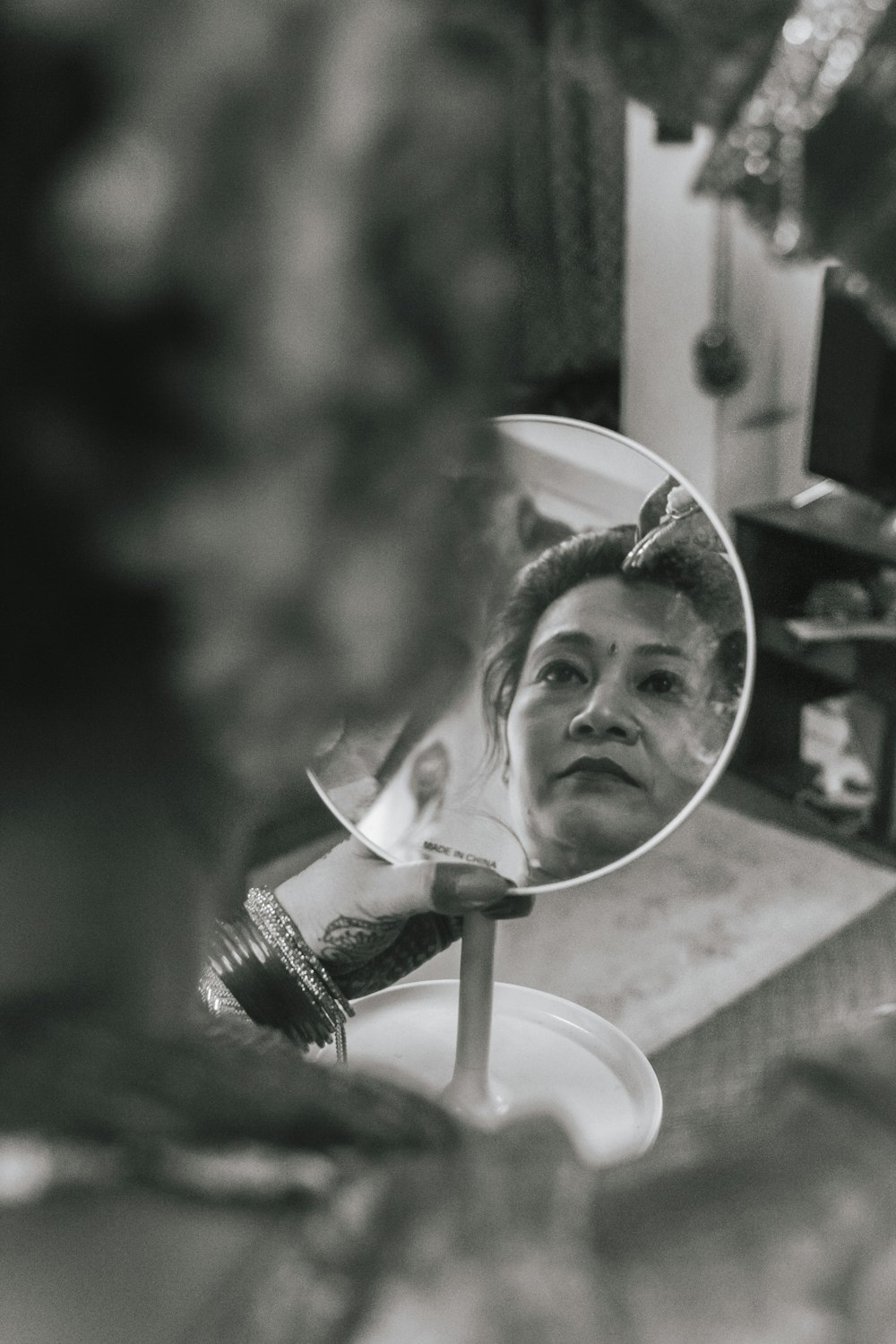 grayscale photo of girl in white shirt holding mirror