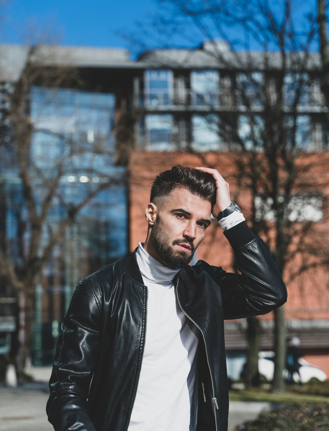 man in black leather jacket holding black smartphone