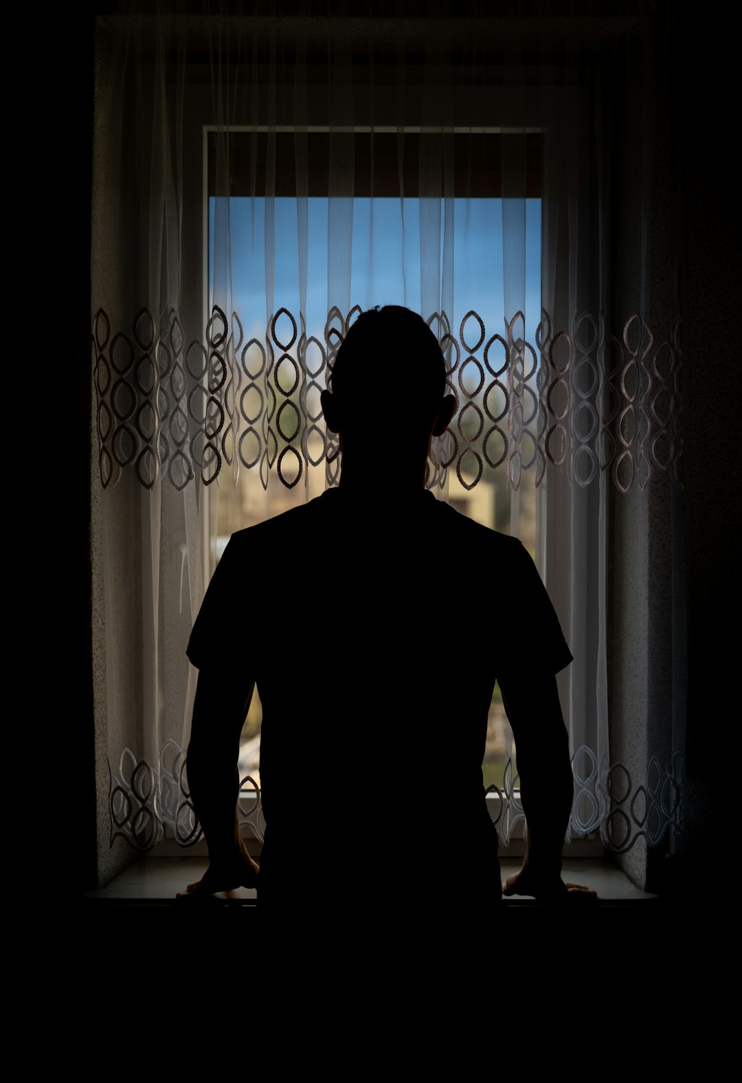 silhouette of man standing near window