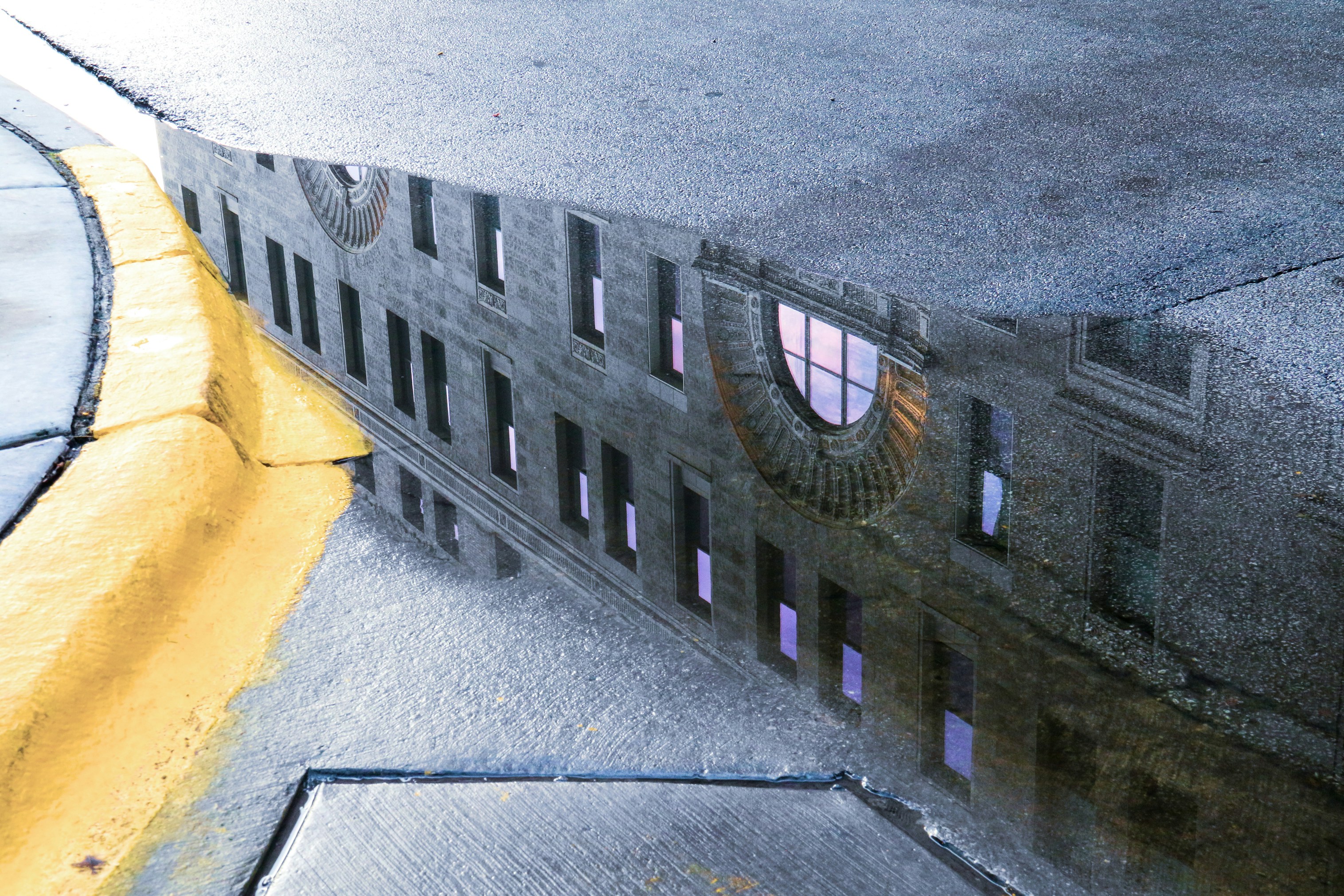 black and white concrete building, One of the buildings in central Chicago, reflected in rainwater on the highway.