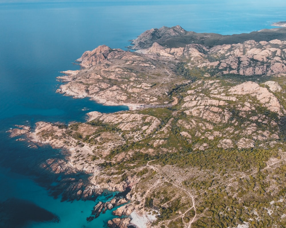 aerial view of green and brown mountains and blue sea during daytime