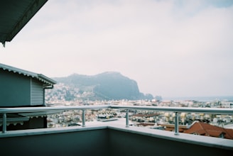 Sunset view from a balcony overlooking a quiet cityscape with mountains.