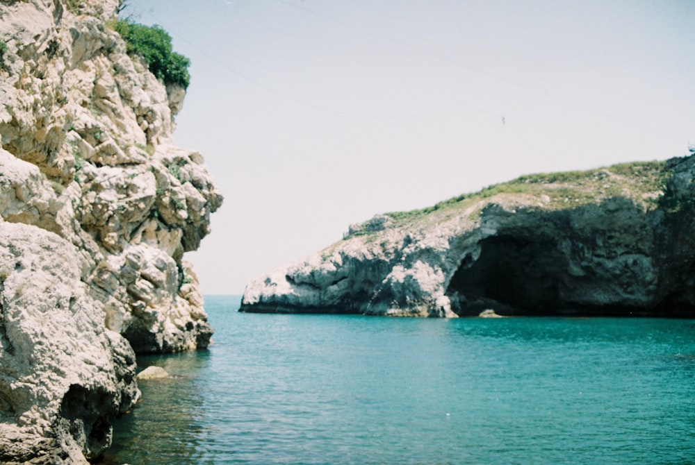 gray rocky mountain beside blue sea under blue sky during daytime