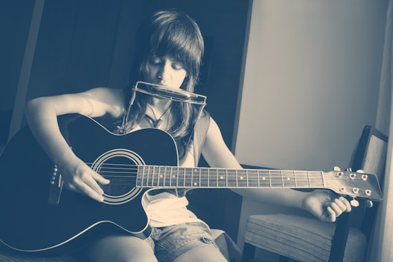 woman in black tank top playing acoustic guitar