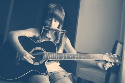 woman in black tank top playing acoustic guitar