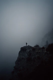 A shadowy figure standing at the edge of a foggy abandoned town at dusk.