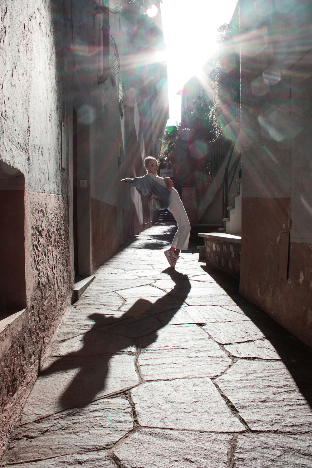 woman in white long sleeve shirt and gray pants standing on gray concrete floor during daytime