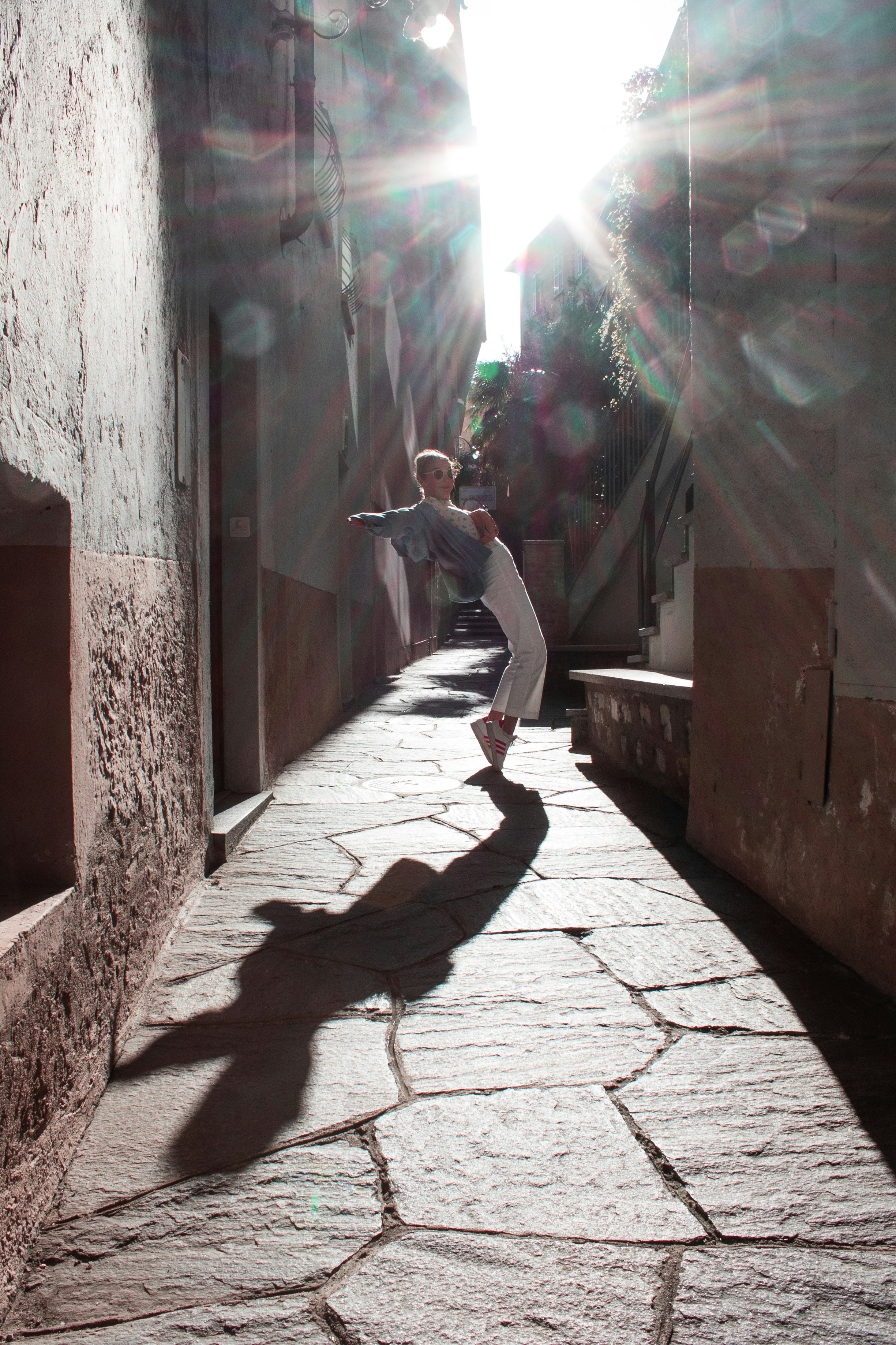 woman in white long sleeve shirt and gray pants standing on gray concrete floor during daytime