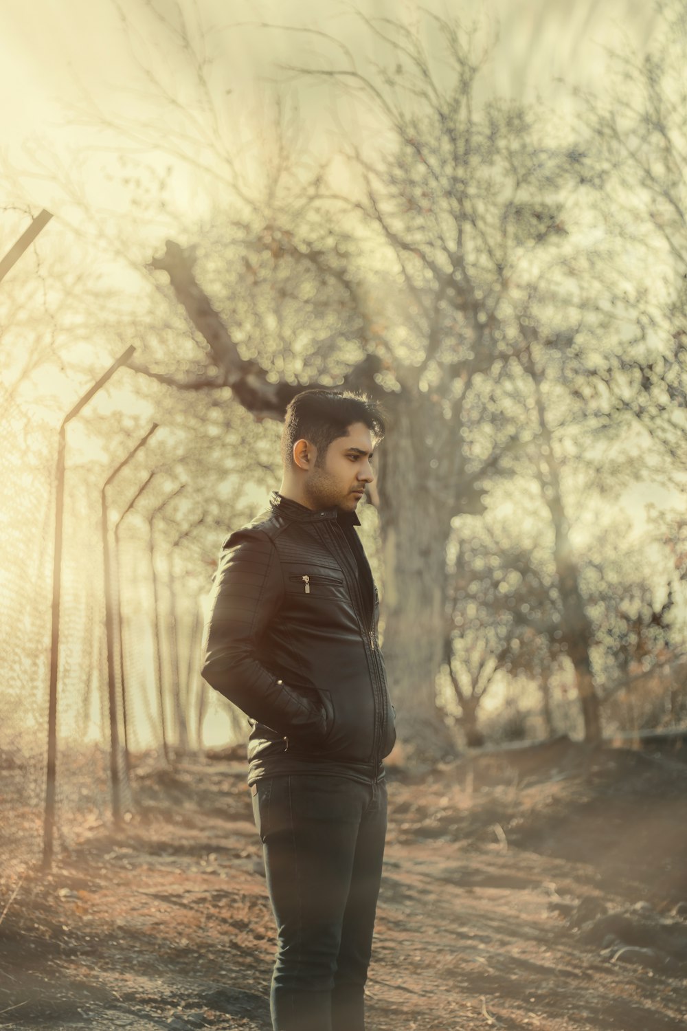 man in black leather jacket standing near trees during daytime
