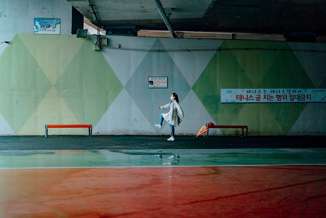 man in white long sleeve shirt and black pants walking on track field