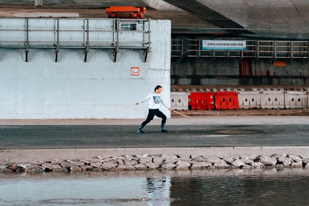 man in white jacket and black pants walking on sidewalk during daytime