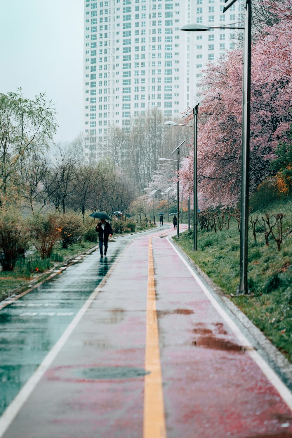 person in black jacket walking on gray concrete road during daytime