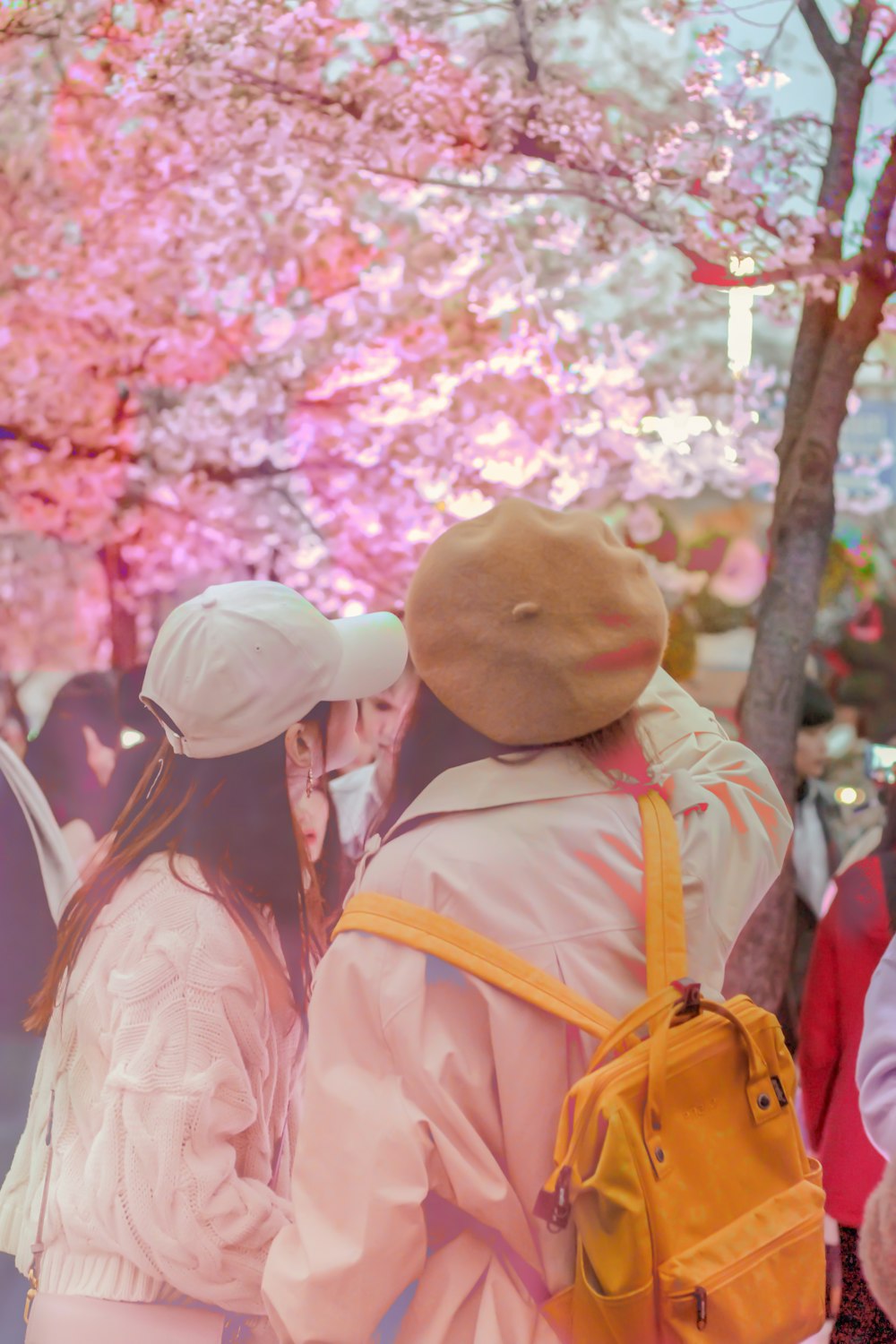 man in orange jacket standing near cherry blossom trees during daytime