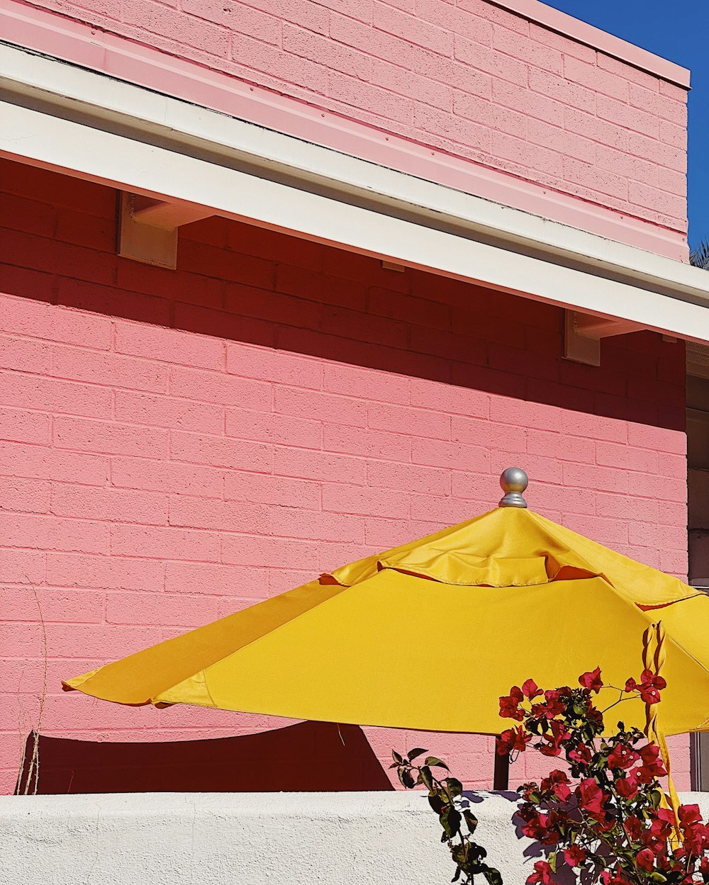 red and yellow umbrella near brown brick wall