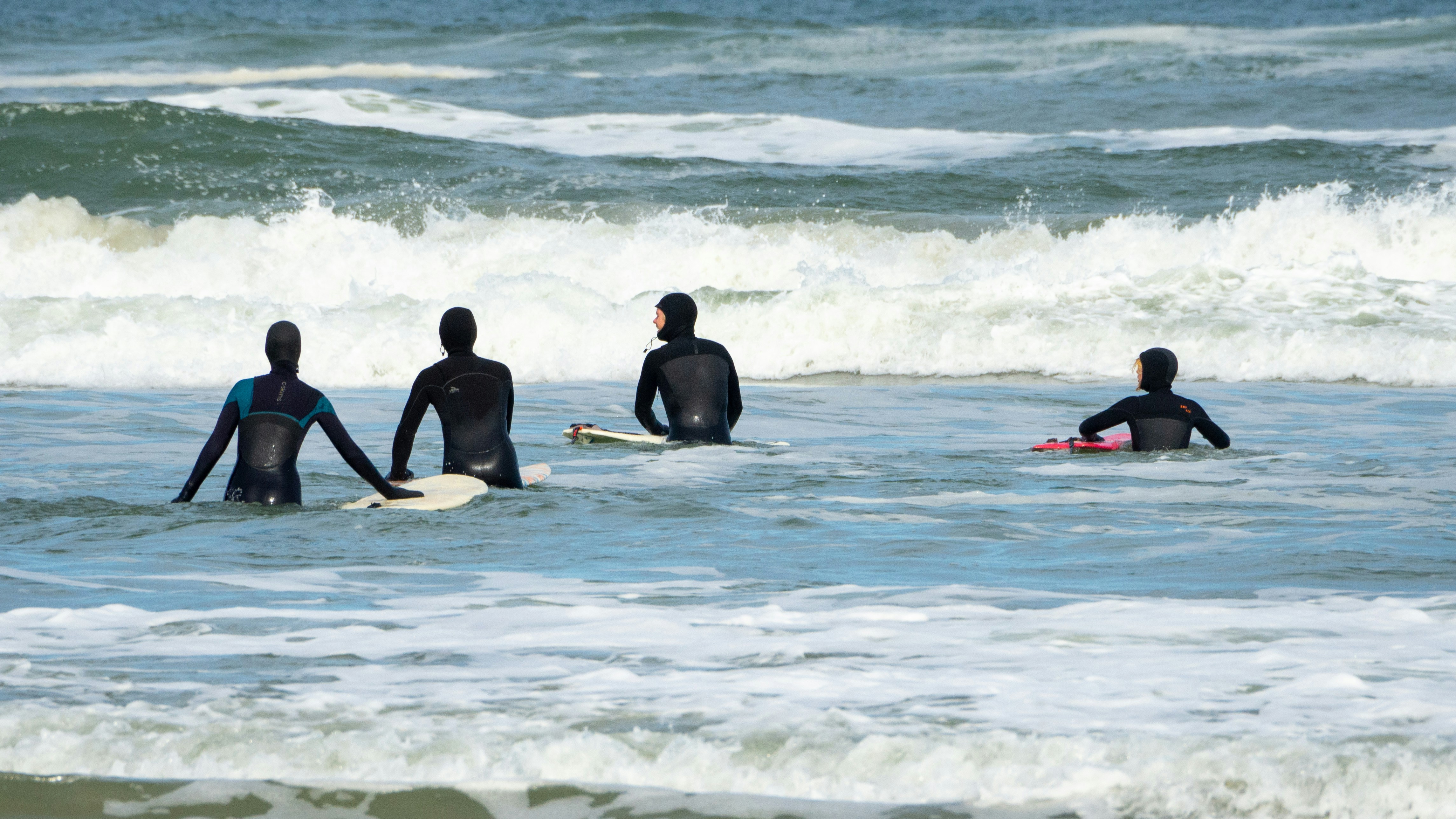 2 men surfing on sea waves during daytime