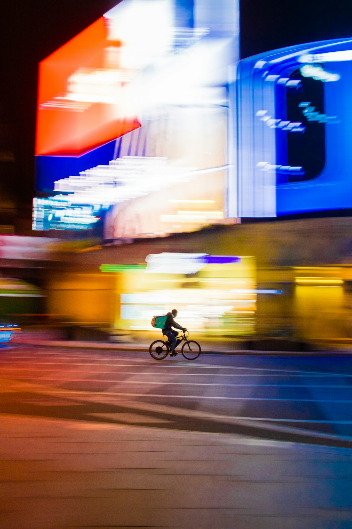 Food delivery cyclist riding through a city at night with a thermal delivery bag