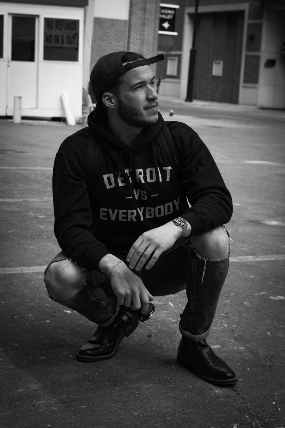 man in black hoodie and black pants sitting on the ground